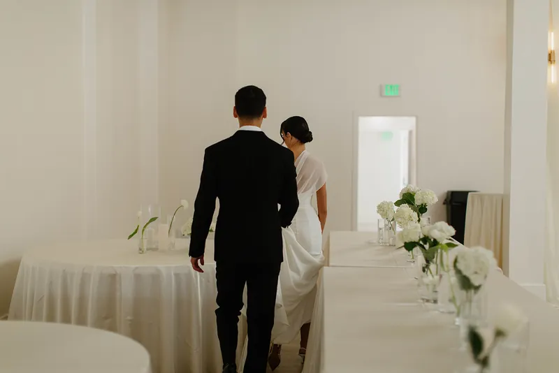 Bride and groom walking past set tables at Moments on Main, Payson