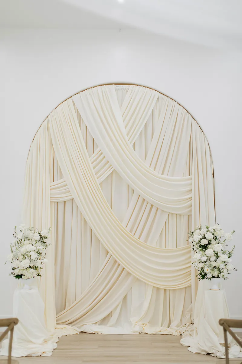 Draped ceremony arch with white florals at Moments on Main, Payson