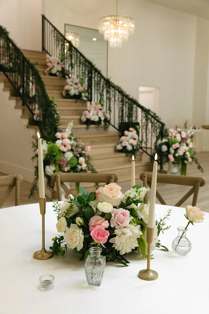 Table florals and candles with the staircase behind at Moments on Main