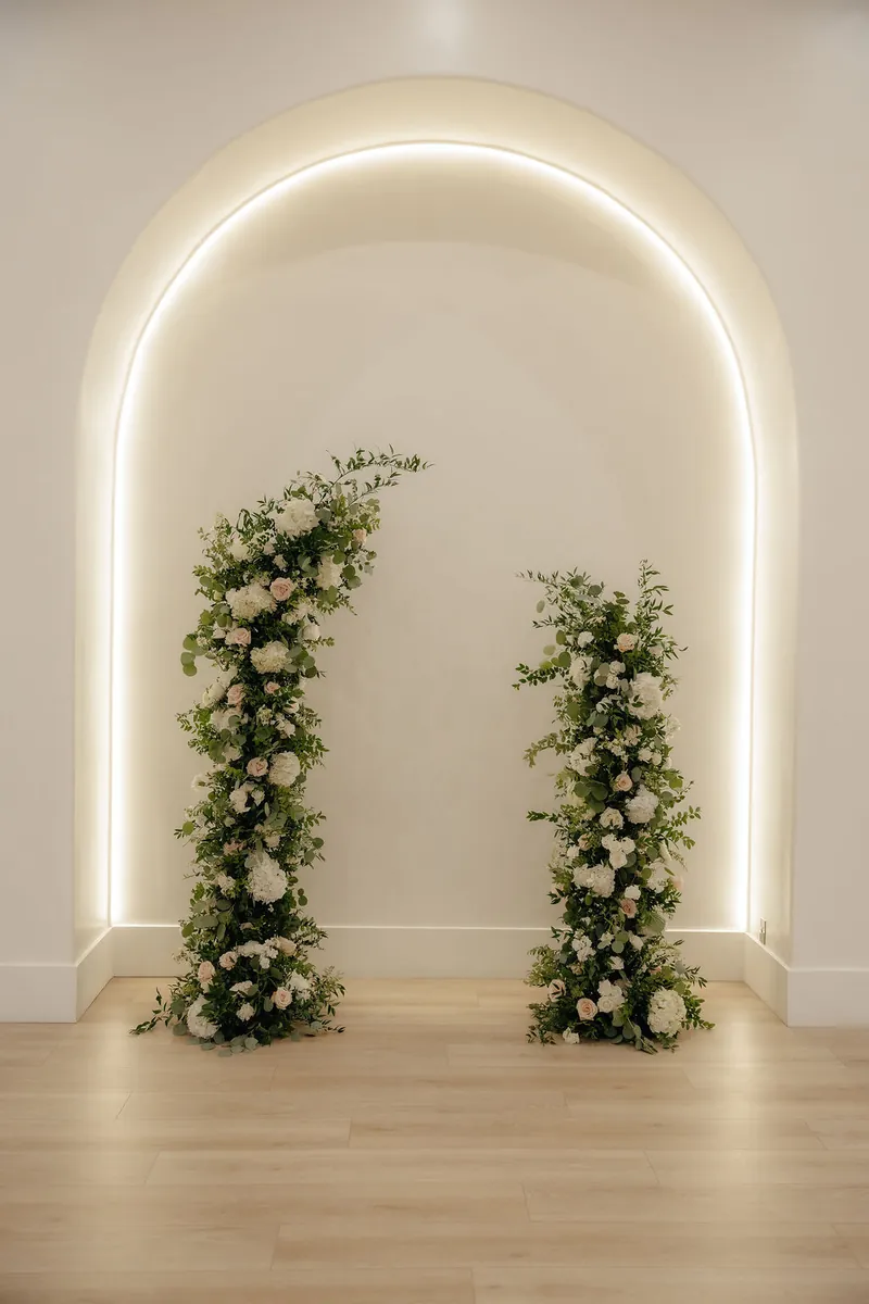 Lit arch with floral pillars in the ceremony space at Moments on Main, Payson