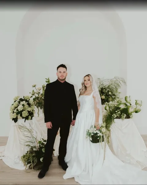 Bride and groom in front of a white floral arch at Moments on Main, from Mette Blackburn's Google review