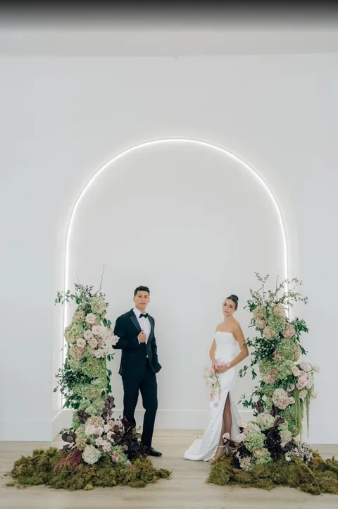 Couple beneath the lit arch with florals at Moments on Main, from Jackie Siggard's Google review