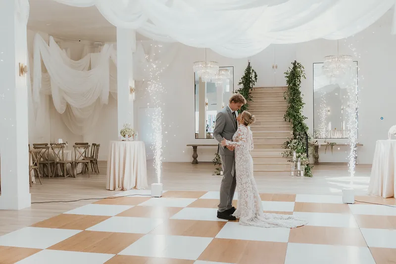 Couple's first dance on the checkered floor with spark fountains either side of the staircase